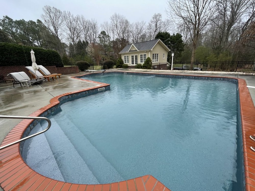 Crisp blue pool with brick coping and clean, well-kept decking